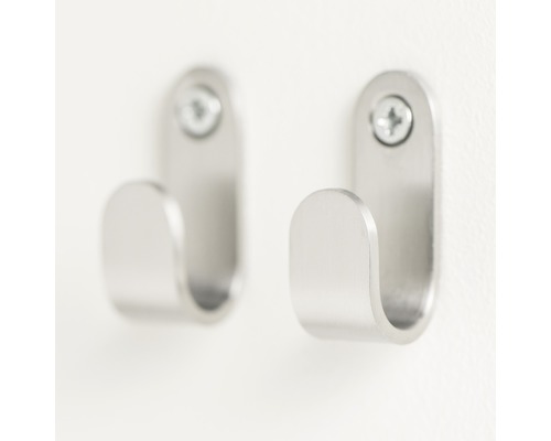 Zwei silberfarbene Kleiderhaken aus Metall mit Schrauben an einer Wand befestigt.