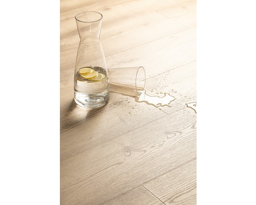 Scène décorative avec une carafe d''eau avec des tranches de citron et un verre renversé sur un plancher en bois clair