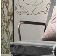Detailaufnahme eines Sessels mit Kissen vor einer Wand mit floralem Muster