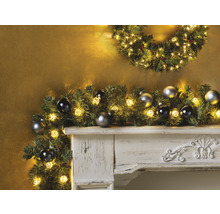 Cheminée décorative avec guirlande de Noël, lumières et boules de Noël.