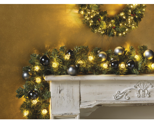 Cheminée décorative avec guirlande de Noël, lumières et boules de Noël.