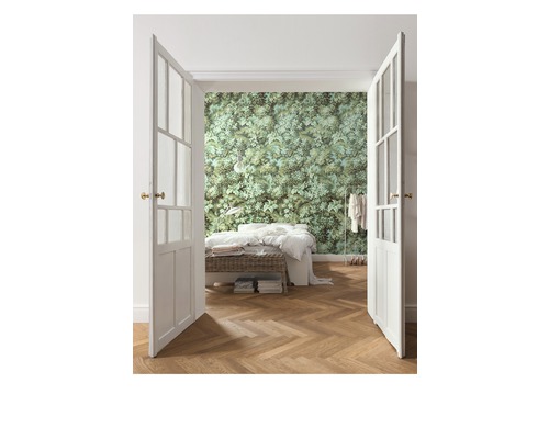 Chambre avec lits doubles, plancher en bois et papier peint à motifs de feuilles derrière une double porte ouverte