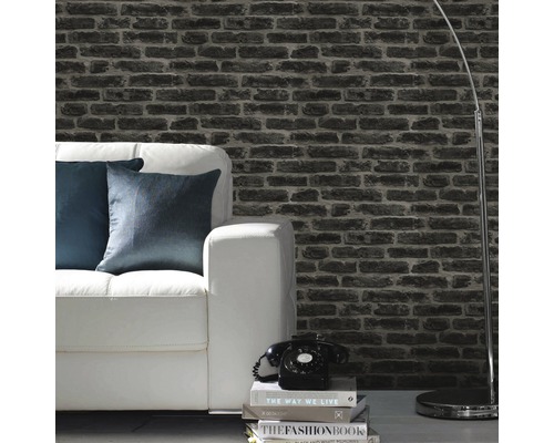 Salon avec papier peint aspect pierre, canapé blanc et lampadaire.