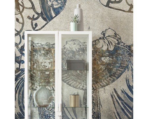 Salon décoratif avec une vitrine blanche devant un papier peint à motifs.