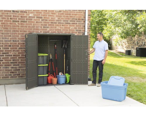 Gartenszene mit einem Lagerschrank aus Kunststoff für Gartengeräte und Aufbewahrungsboxen.