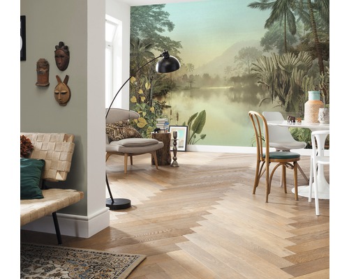 Wohnraum mit tropischer Fototapete, Holzboden im Fischgrätmuster, Sitzmöbeln und Stehlampe.