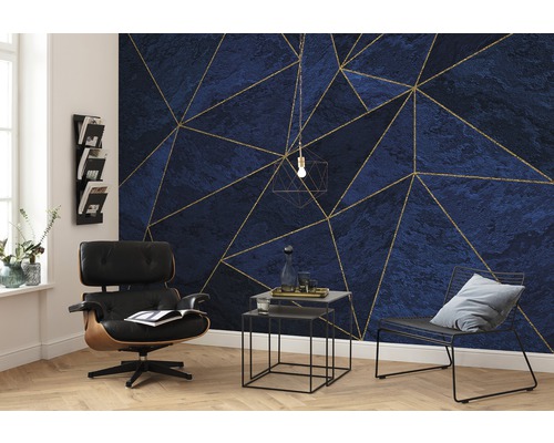 Wohnzimmer mit blau-goldener geometrischer Mustertapete, Sessel und Beistelltischen.