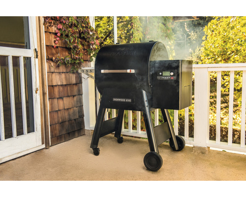 Traeger Ironwood 650 Pelletgrill sur une terrasse avec de la fumée.
