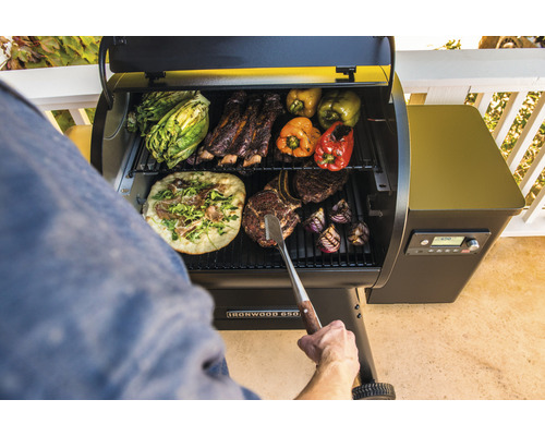 Barbecue avec pizza, côtes levées, steak, poivrons, oignons et laitue sur la grille