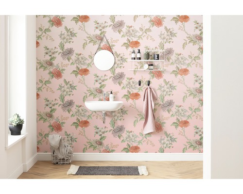 Salle de bain avec papier peint floral, miroir, lavabo et porte-serviettes.