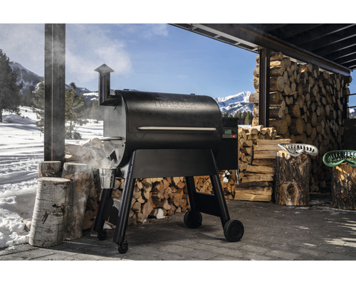 Traeger Grill mit Holzstapel im Hintergrund