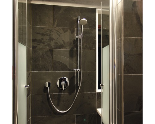 Moderne Dusche mit Armatur und Brause vor dunklem Fliesenhintergrund