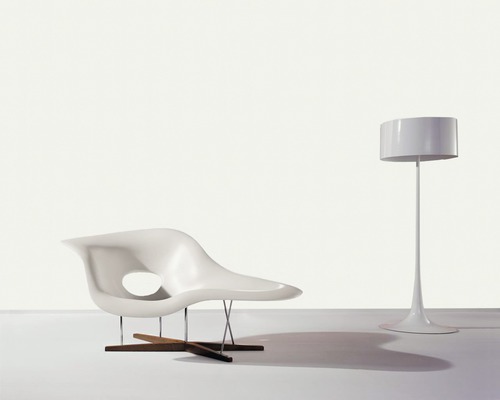 Szene mit Lounge-Sessel aus Kunststoff mit Holz- und Metallgestell und einer Stehlampe.