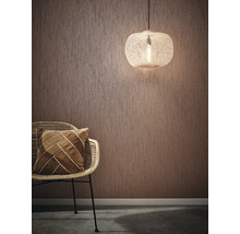 Raumszene mit strukturierten Tapeten, Rattansessel, Kissen und Pendelleuchte