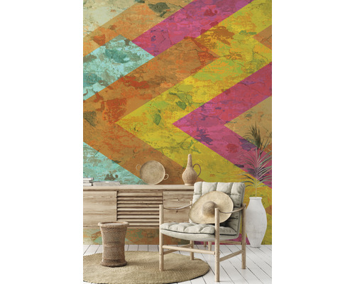 Dekoratives Zimmer mit einem Sessel vor einer Tapete mit geometrischem Muster