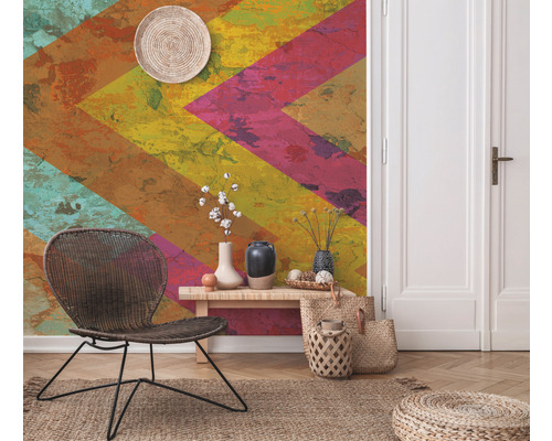 Dekoratives Zimmer mit gemusterter Tapete, Korbstuhl, Beistelltisch und Accessoires