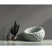 Scène avec un fauteuil rond capitonné, un cactus en pot et une petite sculpture.