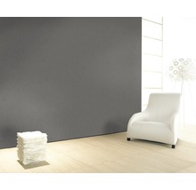 Pièce moderne avec mur gris, plancher en bois clair, fauteuil blanc et lampe.