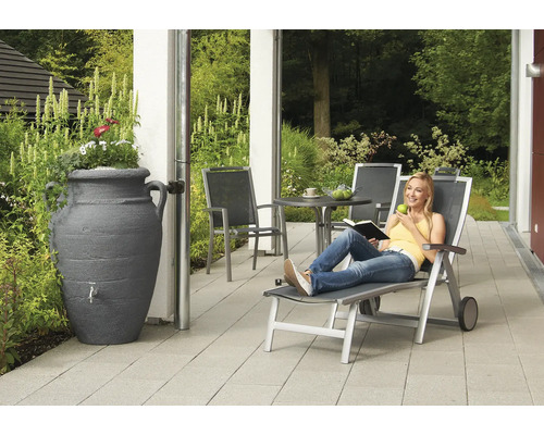 Gartenszene mit Regenspeicher, Gartenmöbeln und entspannender Person