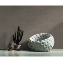 Aménagement de salon avec fauteuil, cactus et figurine décorative devant un papier peint mural