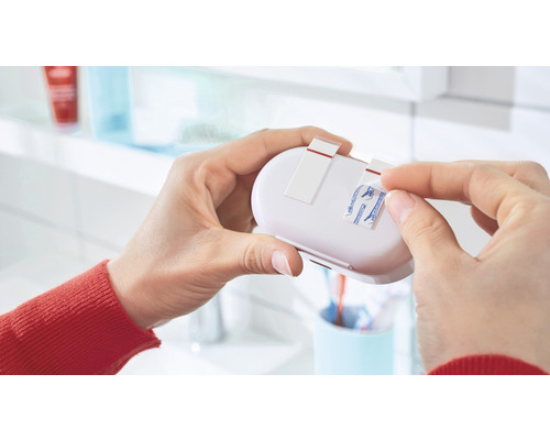 Personne retirant le film protecteur des bandes adhésives d''une étagère de salle de bain