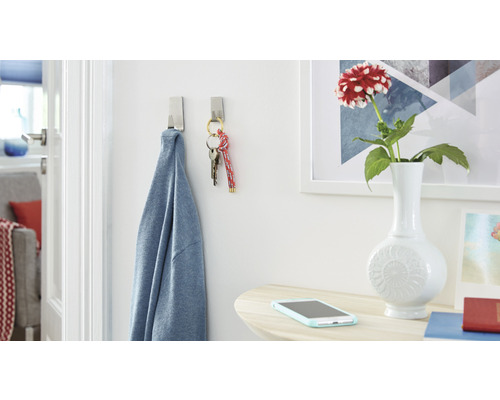 Scène avec deux crochets adhésifs auxquels sont suspendus une chemise et un trousseau de clés, plus une table avec un vase de fleurs et un smartphone