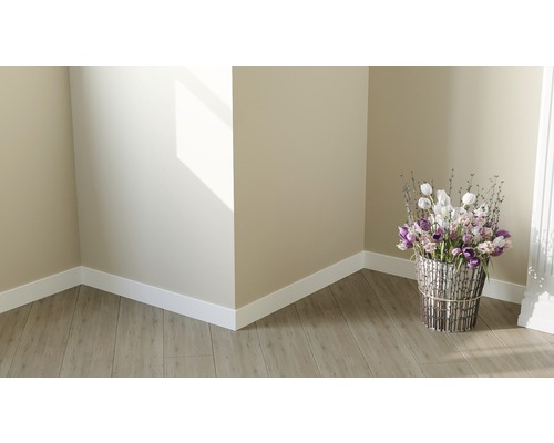 Coin de pièce lumineux avec sol stratifié, plinthes blanches et composition florale