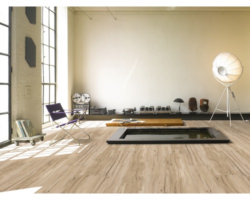 Pièce lumineuse avec grande fenêtre, sol stratifié imitation bois, siège et décorations.