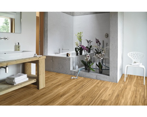 Salle de bains lumineuse avec plancher en bois, lavabo avec table en bois, baignoire et chaise