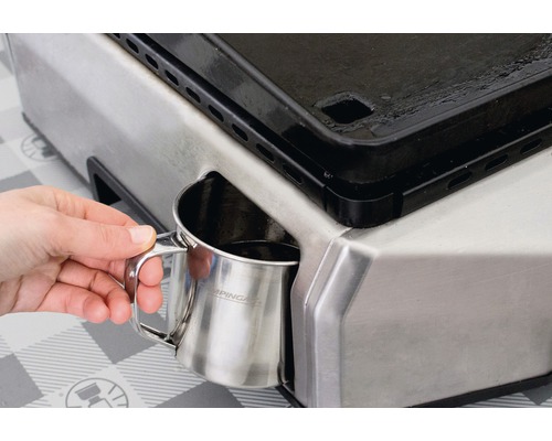 Une personne vide un collecteur de graisse Campingaz dans un gril