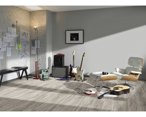 Heller Raum mit Laminatboden, Gitarren, Verstärkern und Sessel.