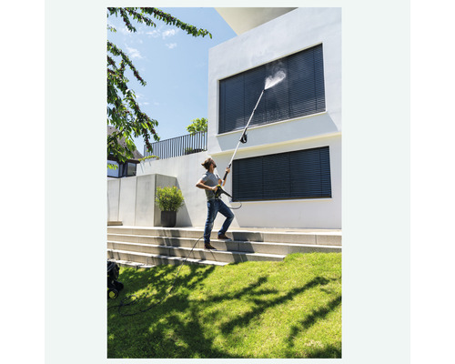 Un homme nettoie les fenêtres d''une maison avec un nettoyeur haute pression.