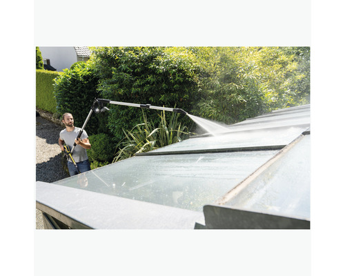 Homme nettoyant le toit d''une serre avec un nettoyeur haute pression et une lance