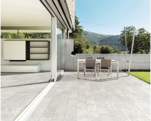 Terrasse avec table et chaises de jardin, sol carrelé et vue sur les montagnes
