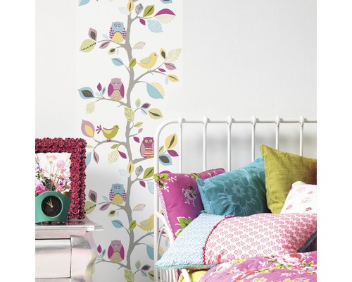 Chambre lumineuse avec lit, table de chevet et papier peint avec motifs d''arbres, d''oiseaux et de hiboux