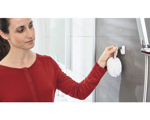 Femme fixant un crochet dans la salle de bain pour une brosse de douche