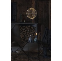 Ambiance de vie décorative avec une boule en fil métallique et des lumières LED, complétée par des fauteuils et une table d''appoint.