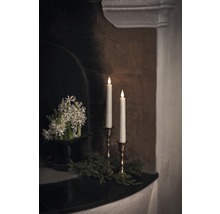 Arrangement décoratif avec bougies, fleurs et verdure sur une cheminée.