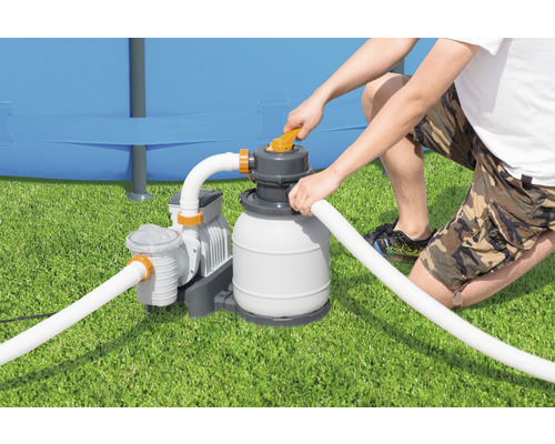 Une personne utilise une installation de filtration à sable pour une piscine sur une pelouse.