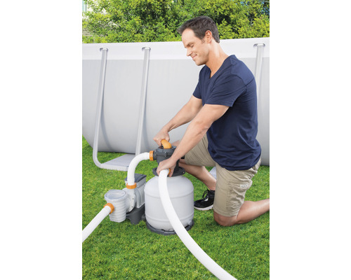 Mann installiert eine Sandfilteranlage für einen Pool im Garten.