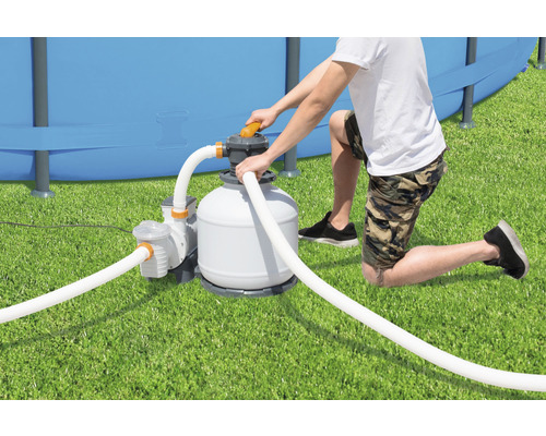 Mann installiert eine Sandfilteranlage für einen Pool im Garten.