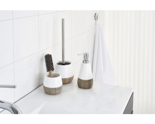 Scène de salle de bain avec distributeur de savon, brosse et ensemble de toilettes sur un lavabo