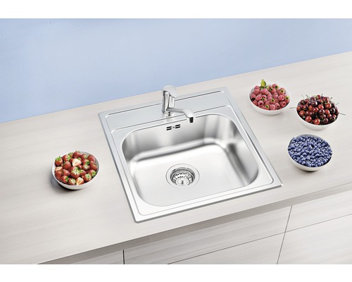 Évier en acier inoxydable avec robinet et bols de fruits sur un comptoir de cuisine