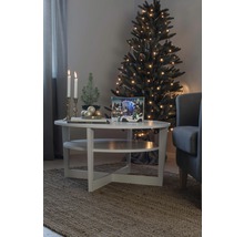 Weihnachtliche Wohnzimmerszene mit Tannenbaum, Lichtern und Dekorationen auf einem Tisch