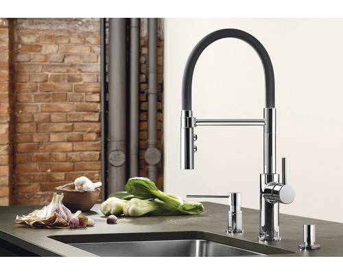 Scène de cuisine avec mitigeur d''évier, distributeur de savon et légumes sur un plan de travail.