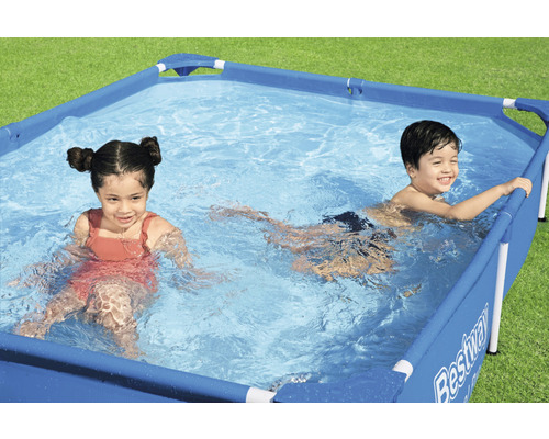 Des enfants se baignent dans une piscine rectangulaire dans le jardin avec le logo Bestway