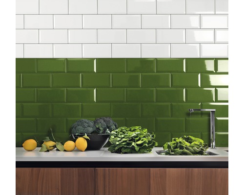 Küchenrückwand mit weißen und grünen Metrofliesen über einer Küchentheke mit Gemüse