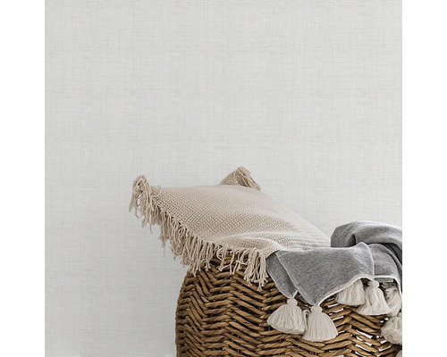 Coussin décoratif et couverture dans un panier en osier devant un mur