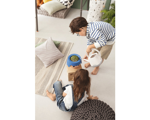 Deux enfants à l''intérieur, dont l''un arrose une plante dans un pot de fleurs avec un visage à l''aide d''un arrosoir.