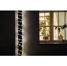 Vue extérieure d''une maison avec une guirlande lumineuse enroulée autour d''un pilier et une fenêtre avec des plantes.